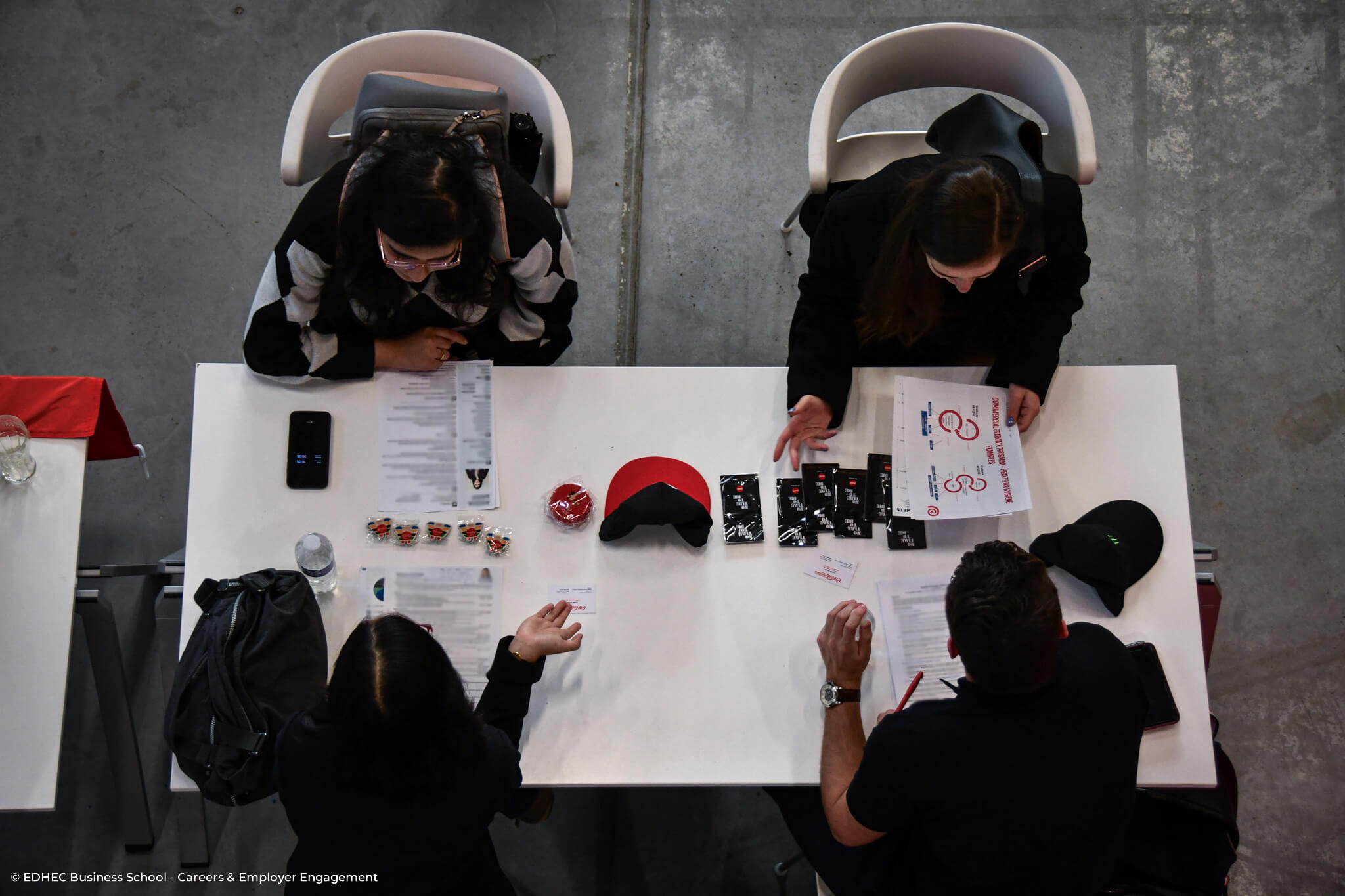 Deux étudiantes assises face à deux recruteurs autour d'une table avec des documents dans les mains
