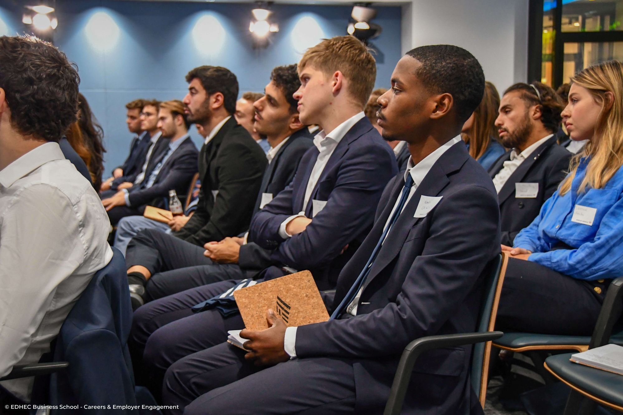 Etudiants en costume assis lors d'une présentation en entreprise